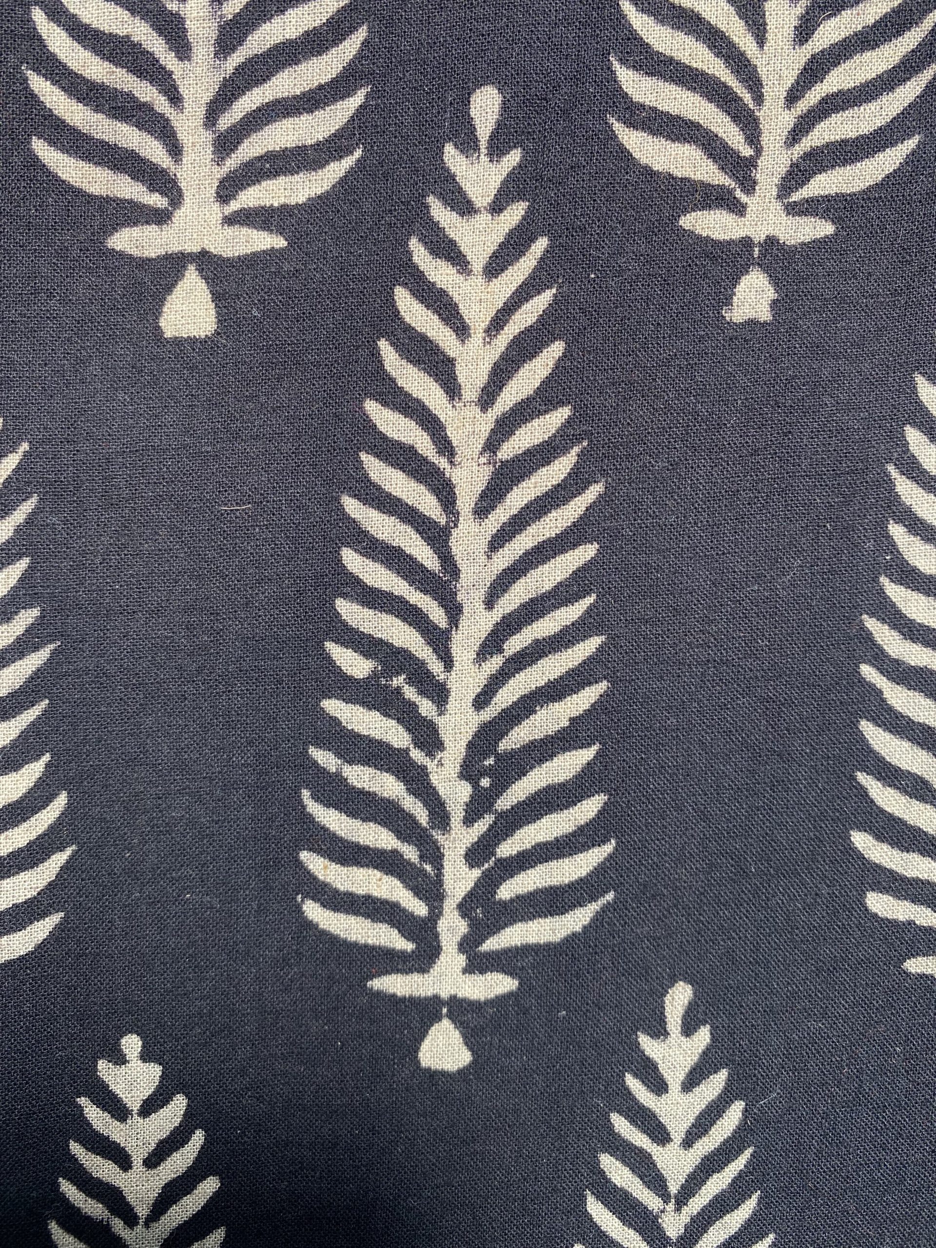 Woven navy fabric with a repeating ivory fern-like pattern onto the dark background