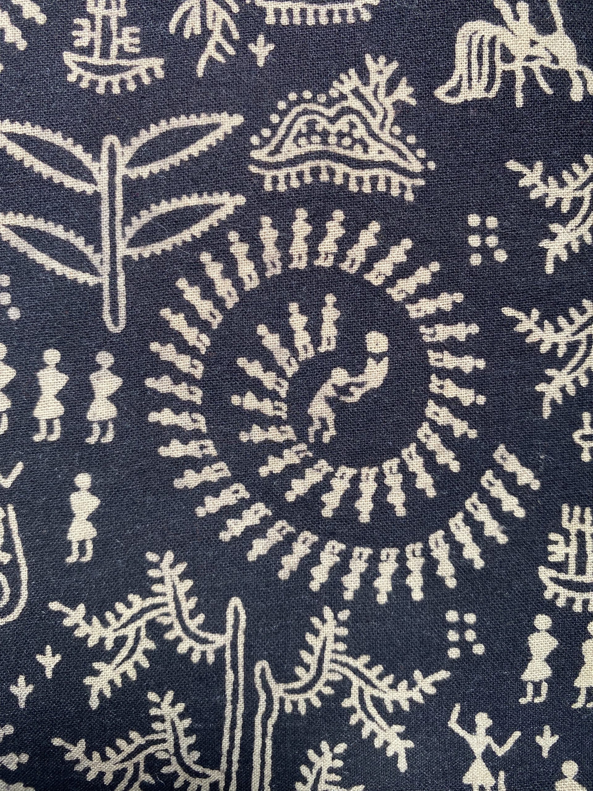 Close-up of dark navy fabric with cream woven botanical and small human silhouettes pattern.