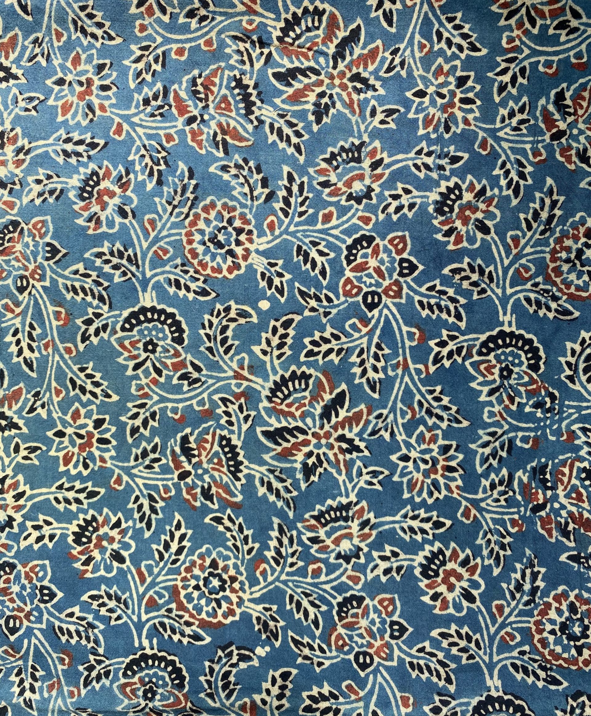 Blue fabric densely patterned with white, black, and red floral motifs on a blue background.