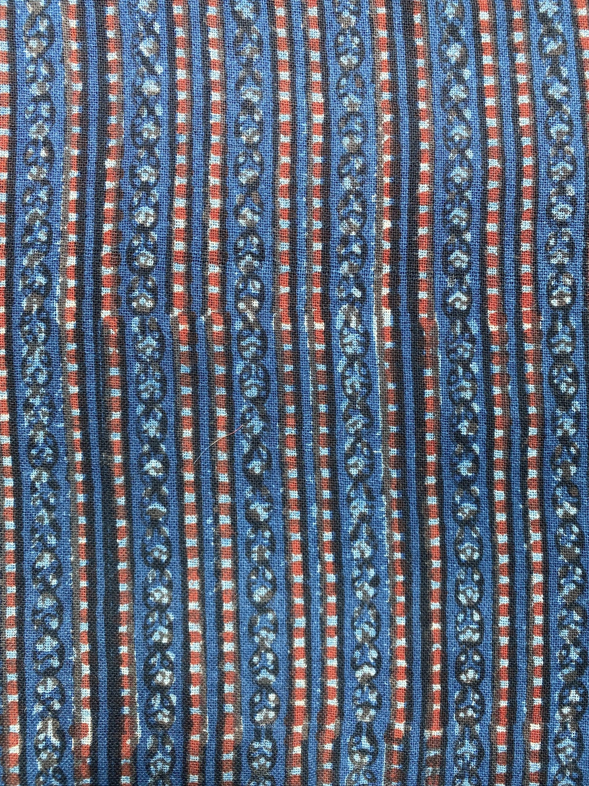 Vertical striped woven fabric in blue with red and white accents and diamond motifs (close-up).
